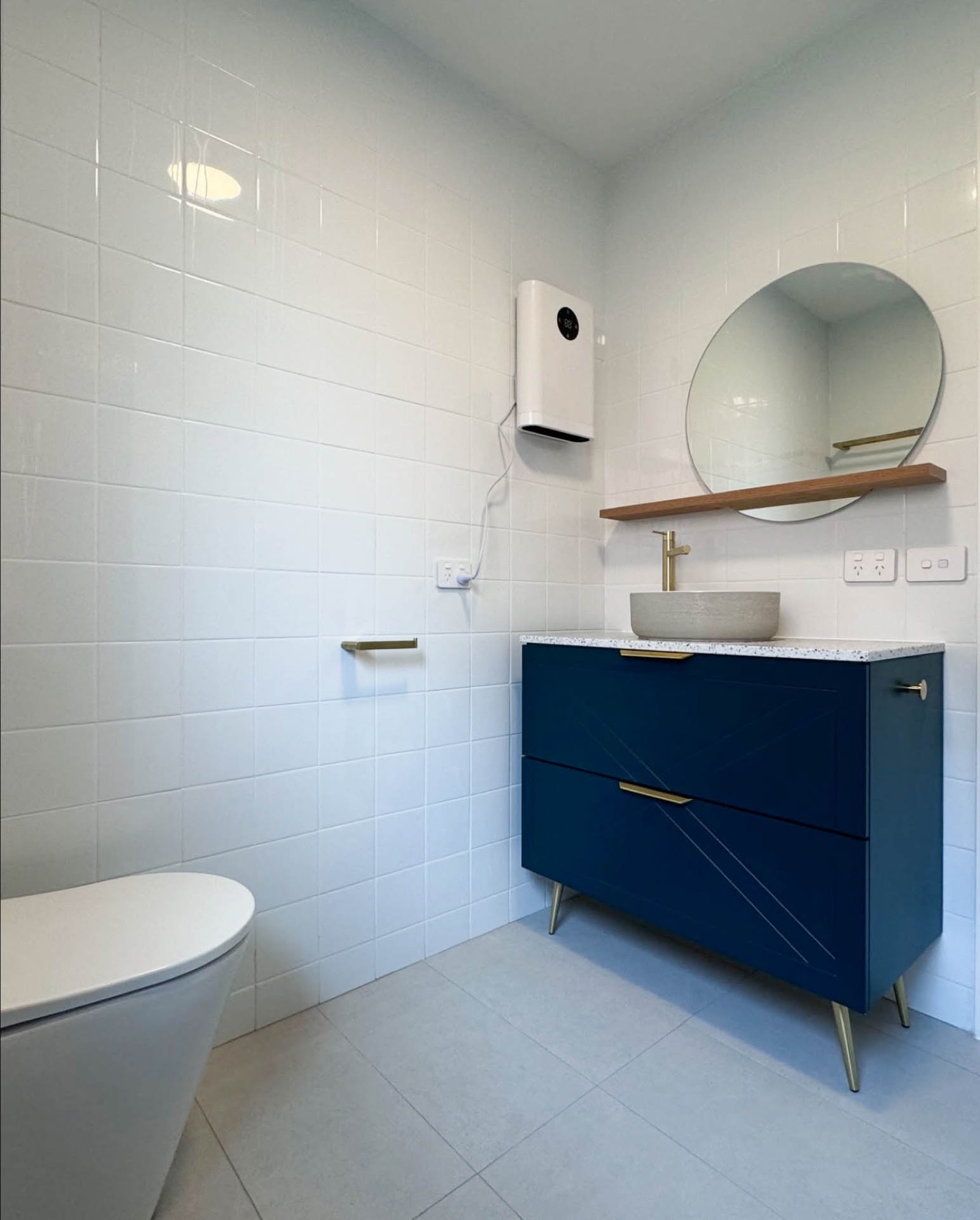 Completed Balaclava bathroom with blue vanity, toilet and full-height white wall tiles