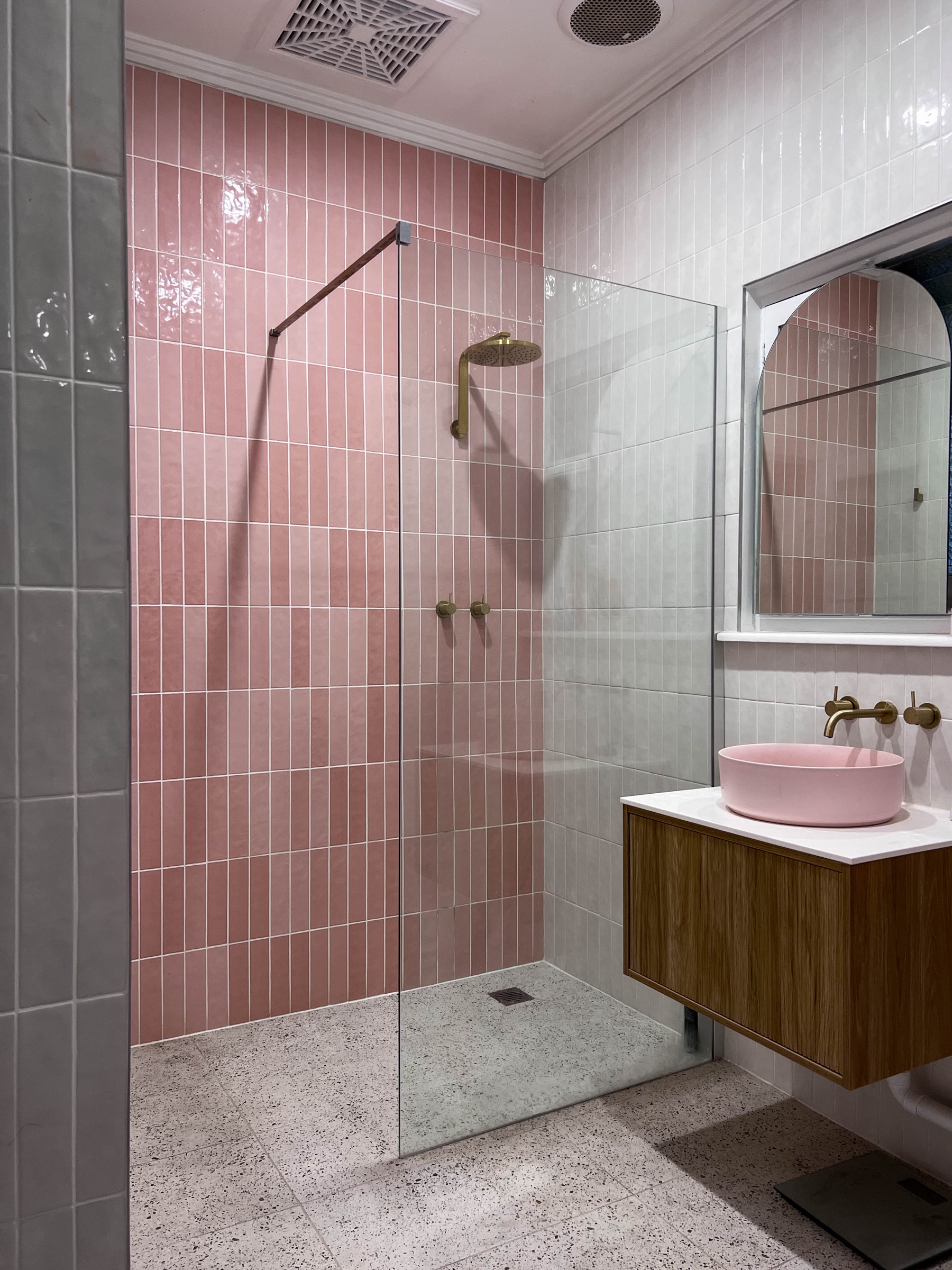 Completed St Kilda bathroom with pink feature tiles, frameless walk-in shower and timber vanity
