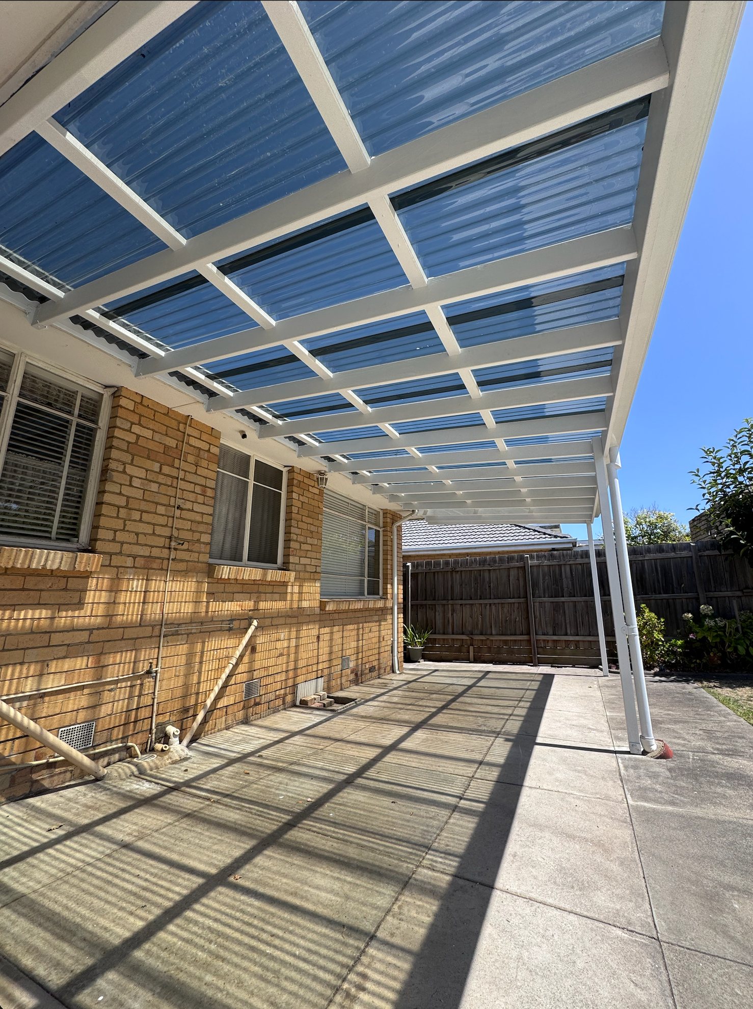 Completed white pergola frame with new clear polycarbonate roofing