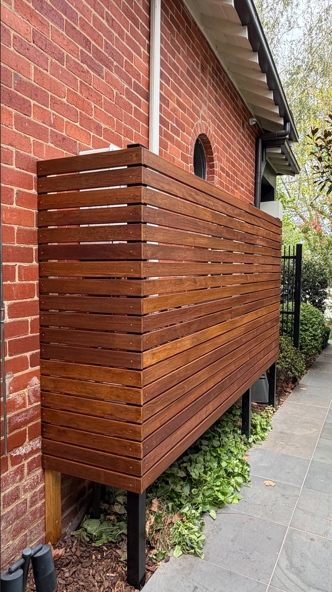 Completed custom Merbau privacy screen beside the red-brick home