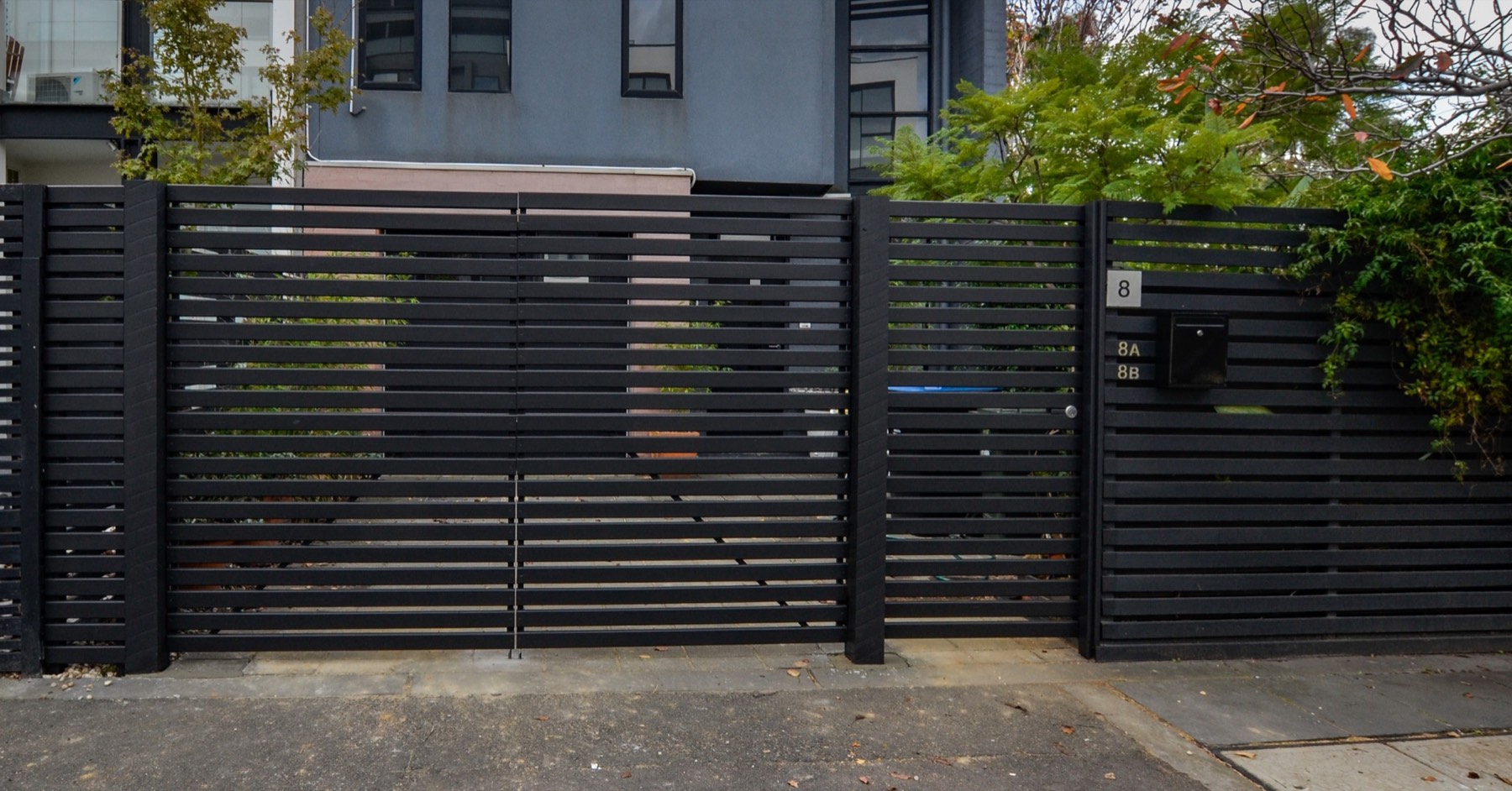 Completed black slatted timber fence, pedestrian gate and double driveway gates — Prahran