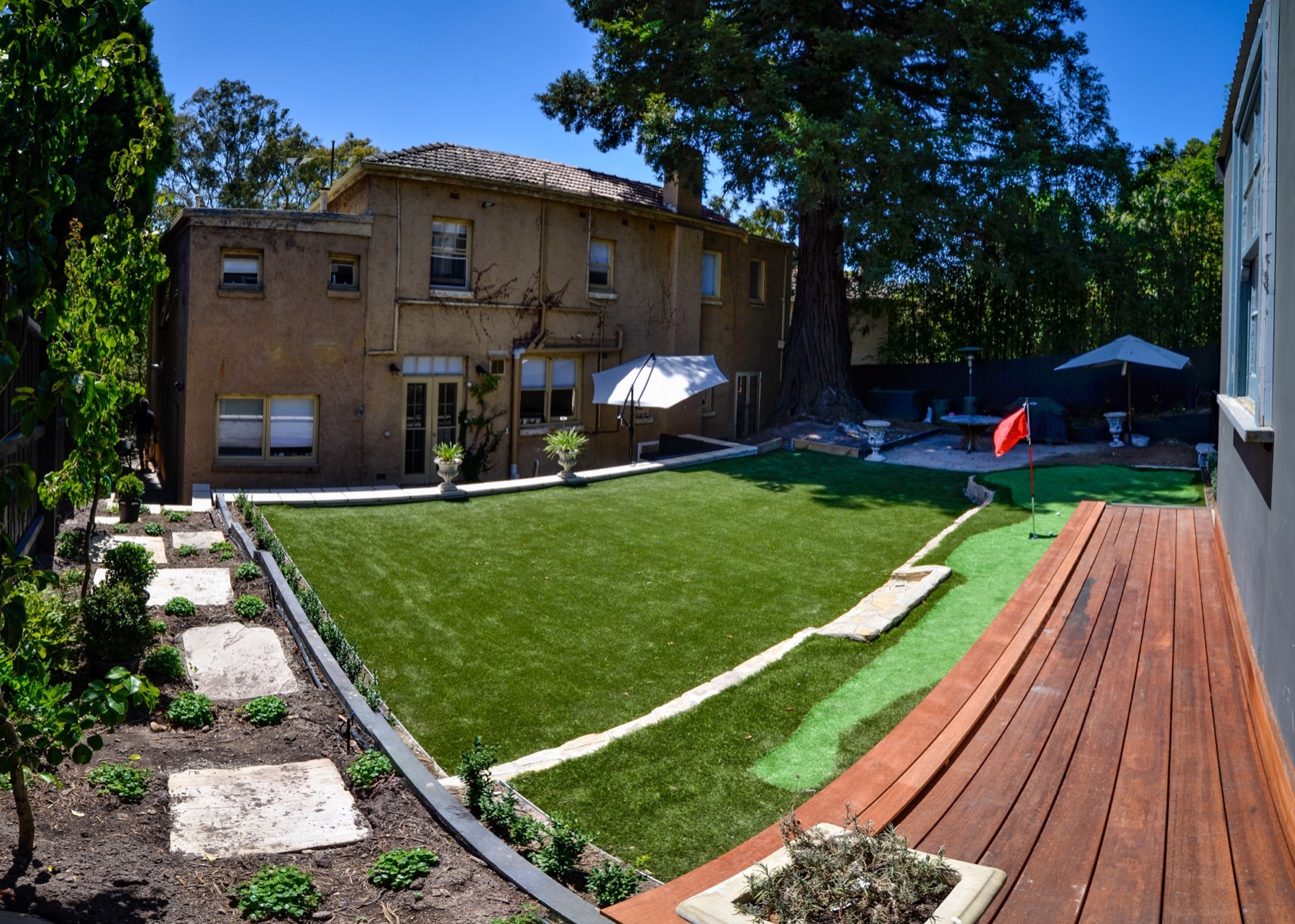 Completed Toorak backyard with artificial turf, stone edging, garden beds and timber platform